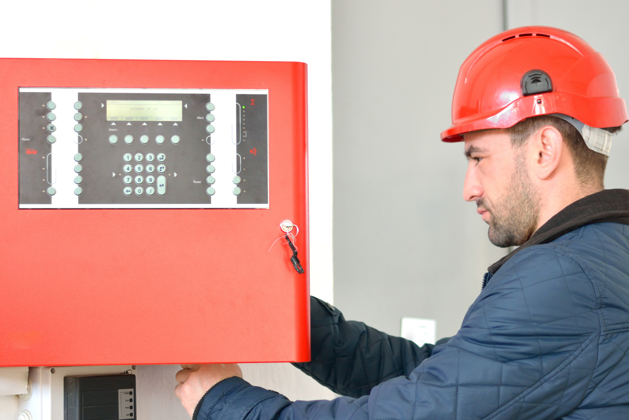 Technician working on a fire alarm control panel.